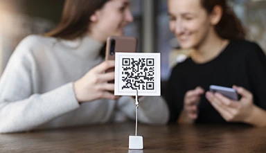 Código QR Argentina - Mujeres jóvenes escaneando código qr en la cafetería